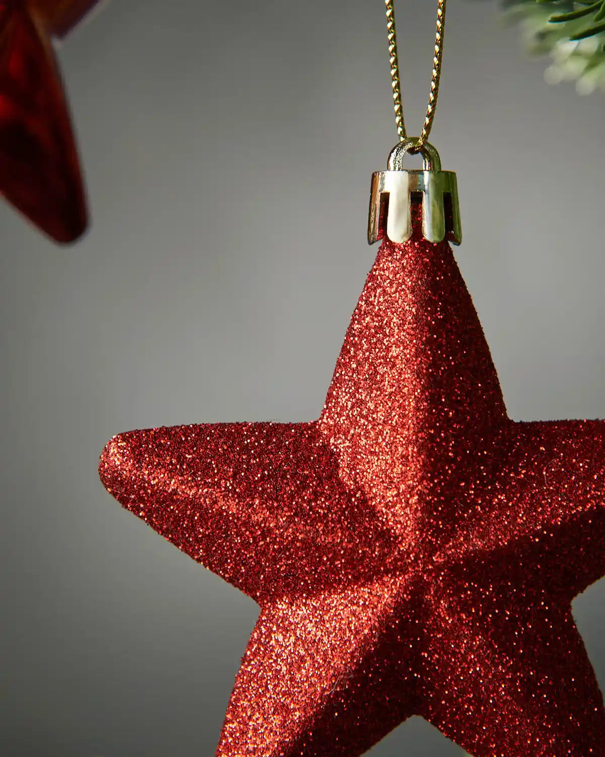 Close up Red glittery star-shaped Christmas ornament on a grey background