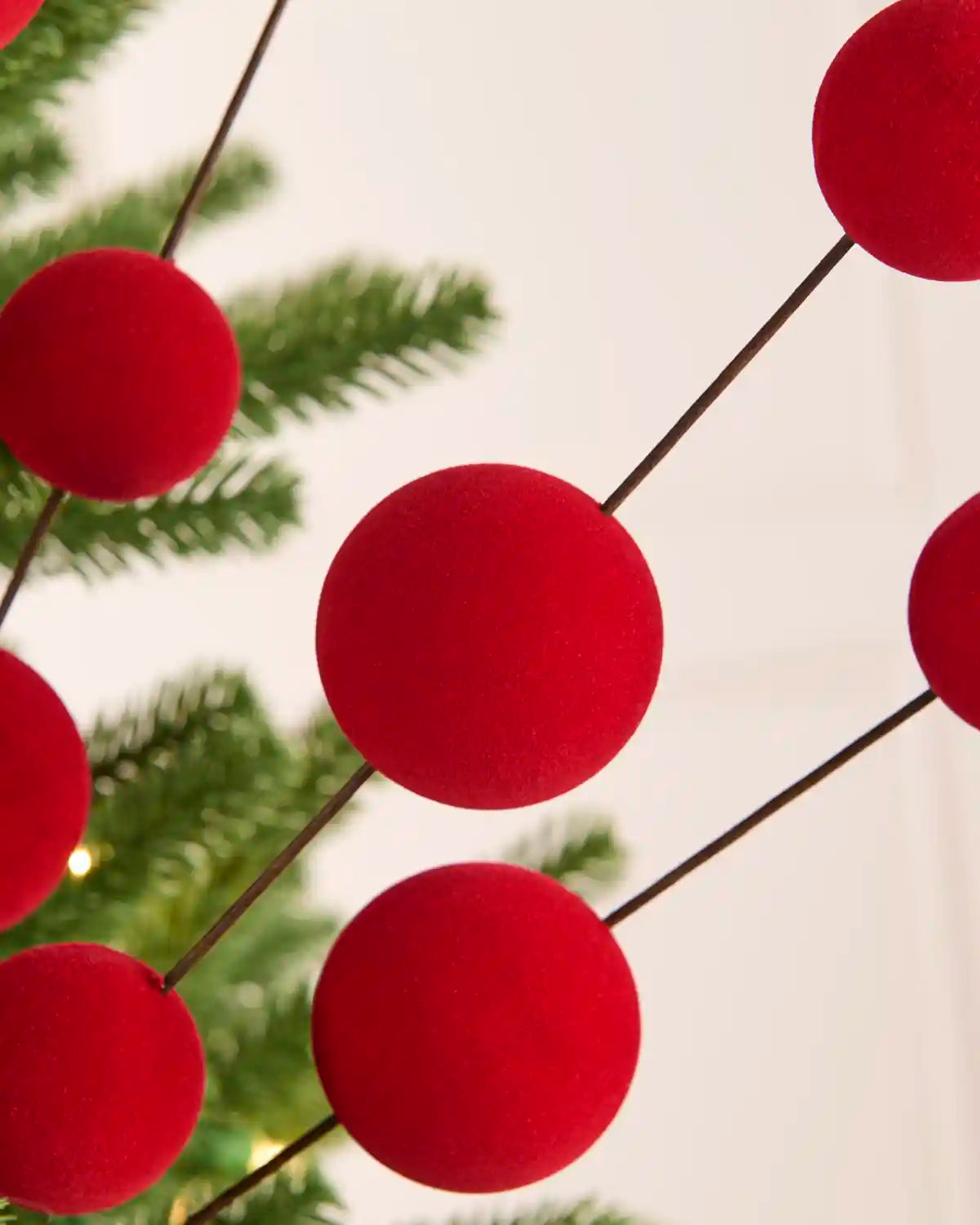 Close up Red velvet bauble pick on a Christmas tree against a light background
