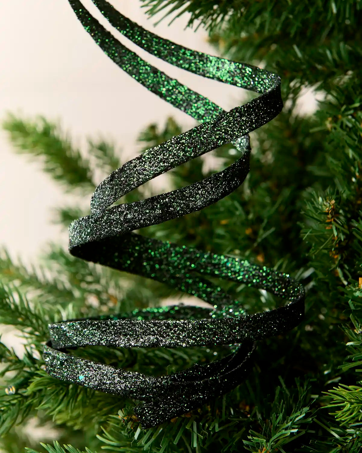 Close up Sage green Glitter Spiral Swirl Pick hanging from Christmas tree