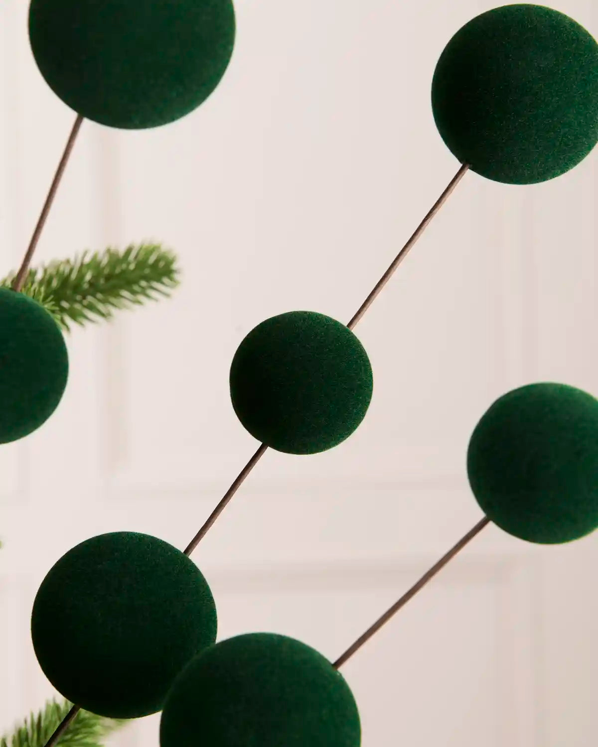 Close up Sage green velvet bauble pick with seven velvet baubles against a light background 