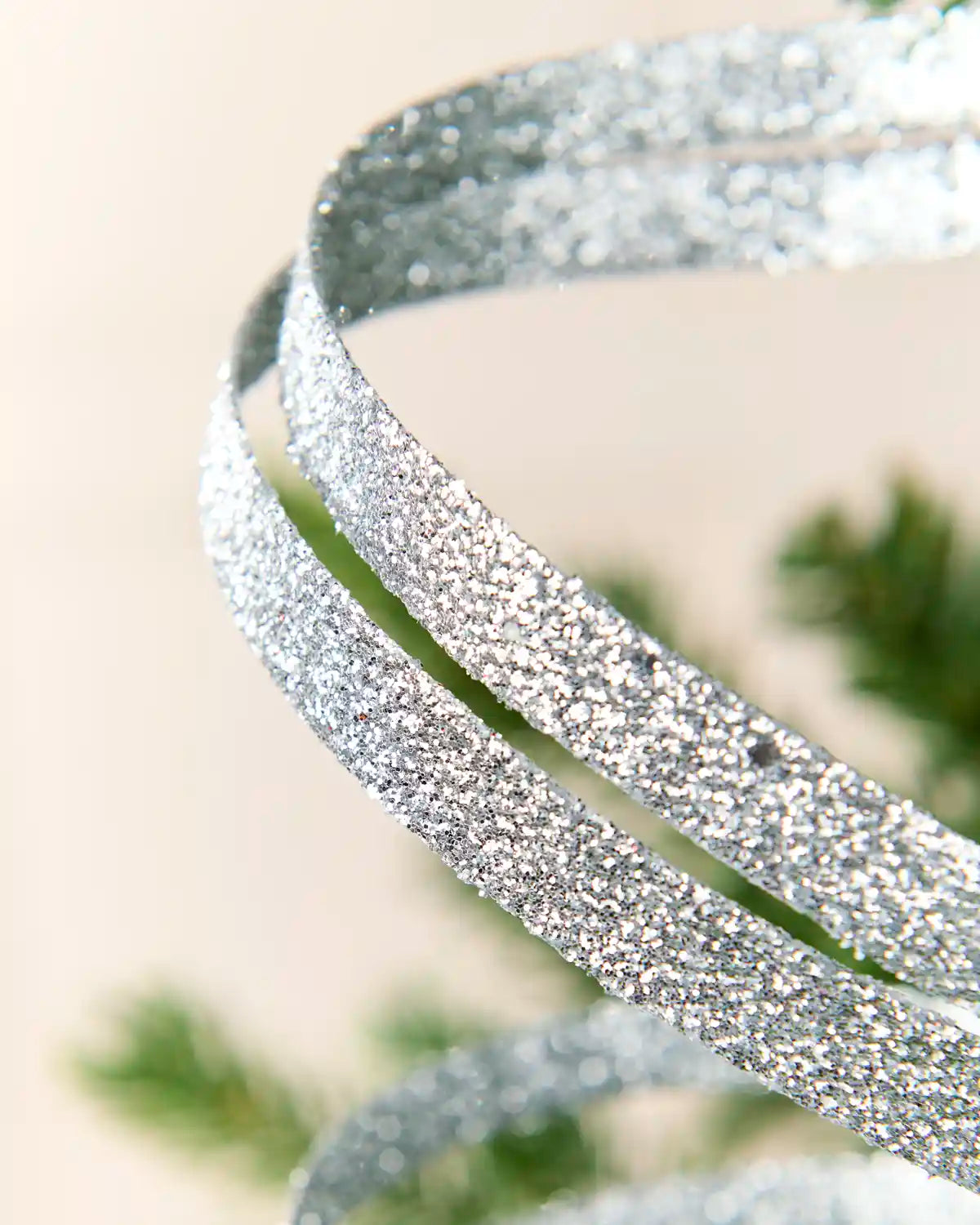 Close up Silver Glitter Spiral Swirl Pick showing Silver glitter details with green and cream blurred background