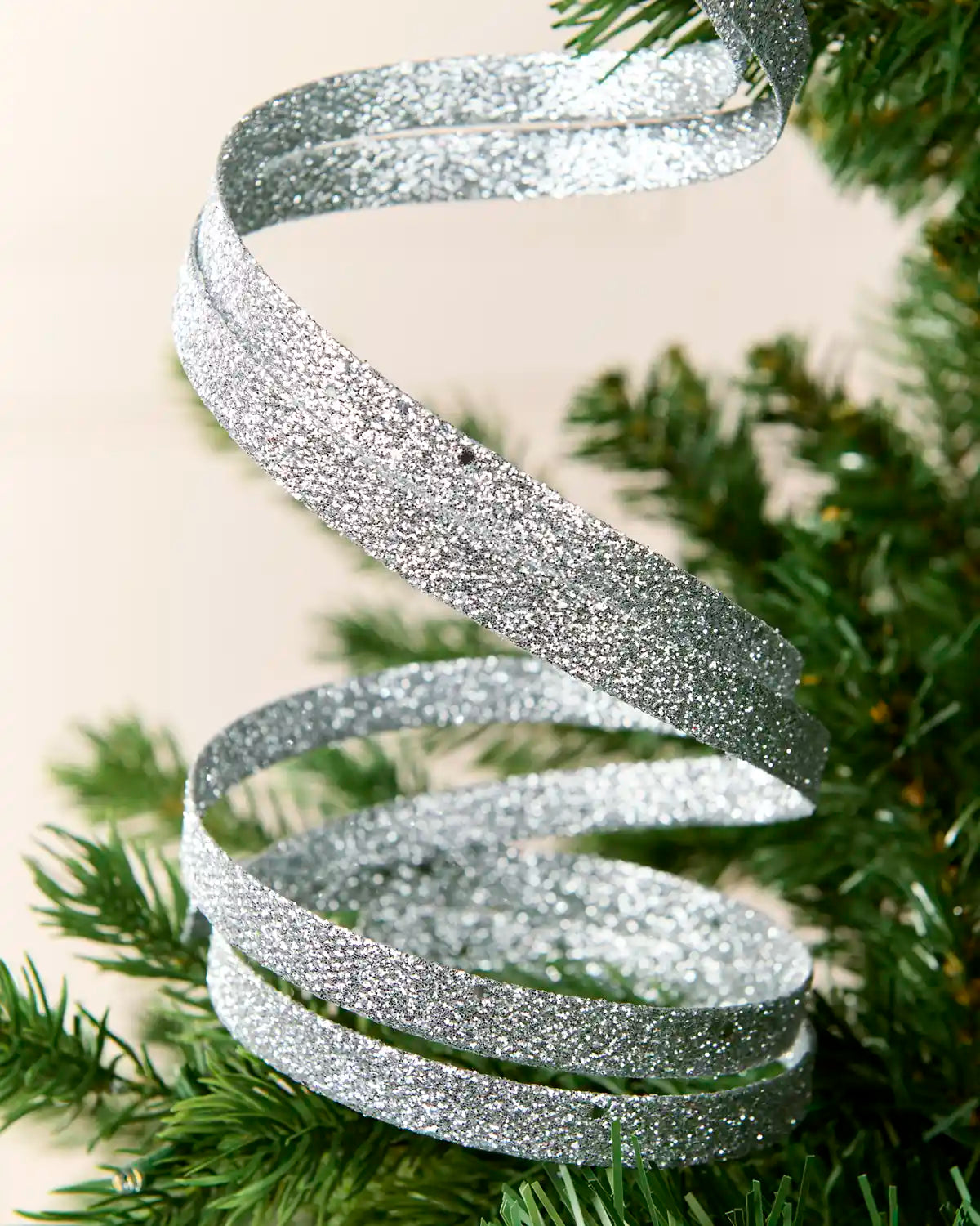 Close up Silver Glitter Spiral Swirl Pick with green and cream blurred background
