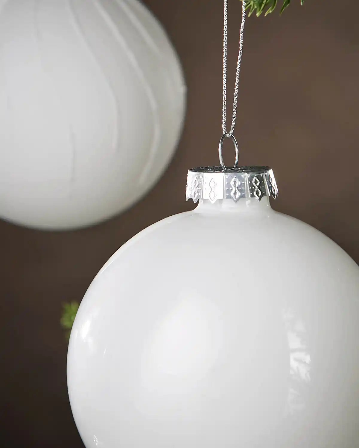 Close up White Christmas ornament with silver top against a blurred background