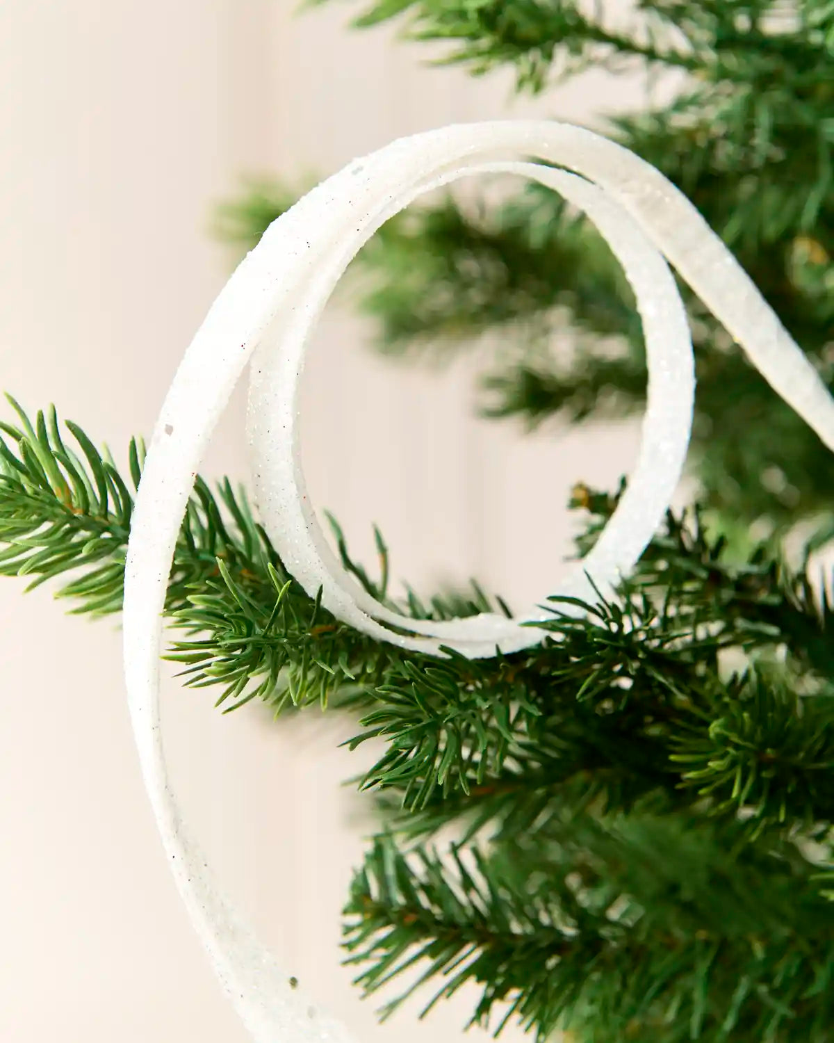 Close up White Glitter Spiral Swirl Pick hanging from Christmas tree

