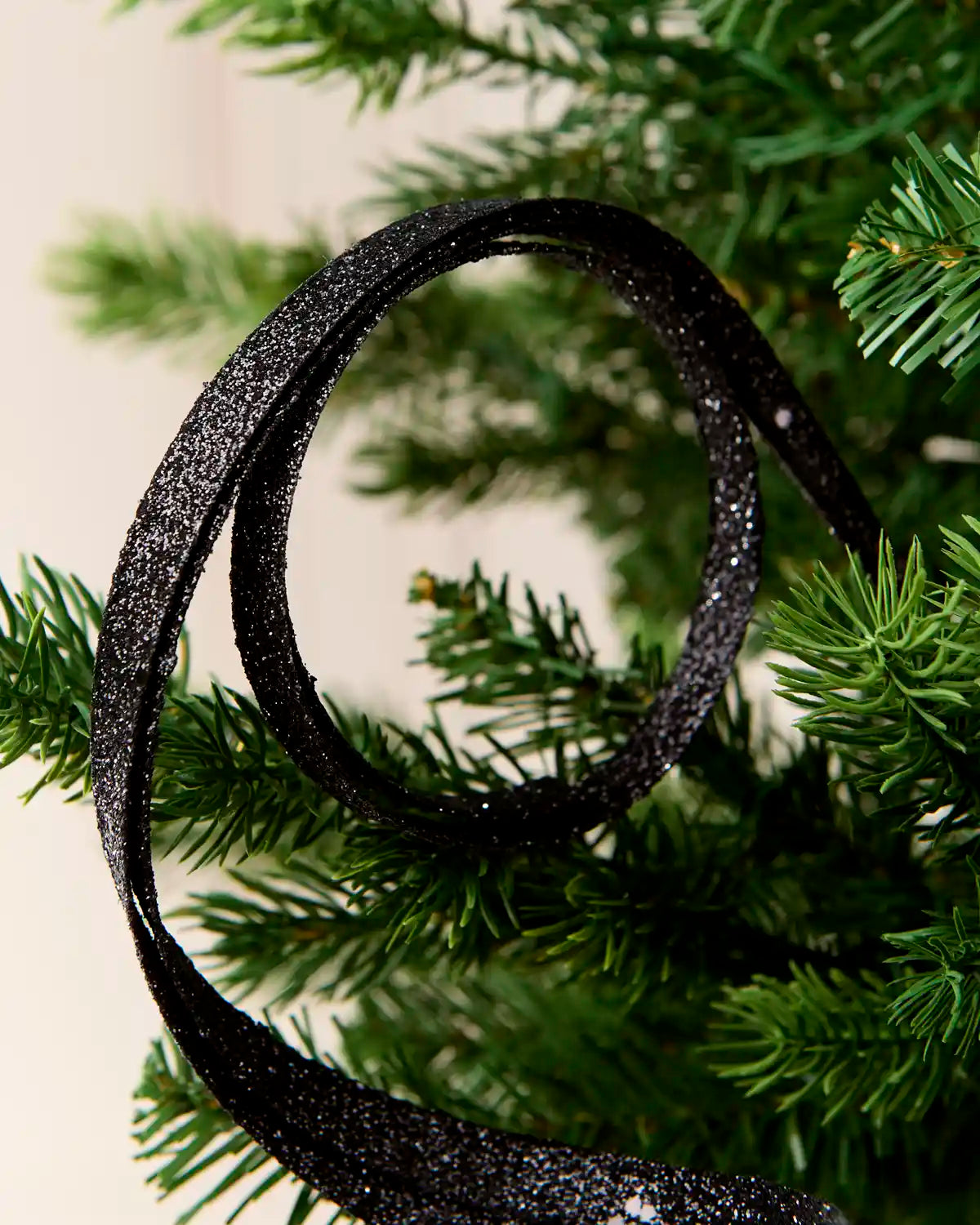 Close up black Glitter Spiral Swirl Pick with green and cream blurred background