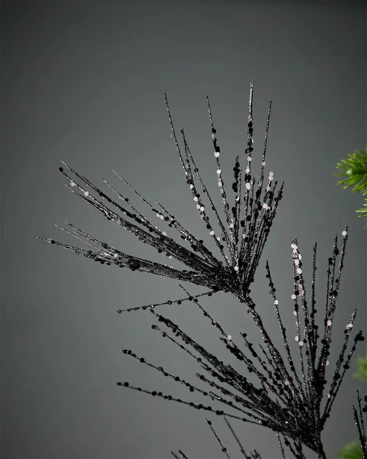 Close-up of black glitter firework spray in front of grey background highlighting sequin detail