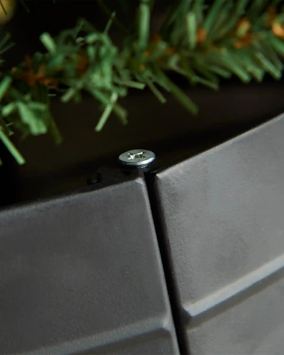 Close-up of black metal tree collar hinges showcasing screw holding hinge 