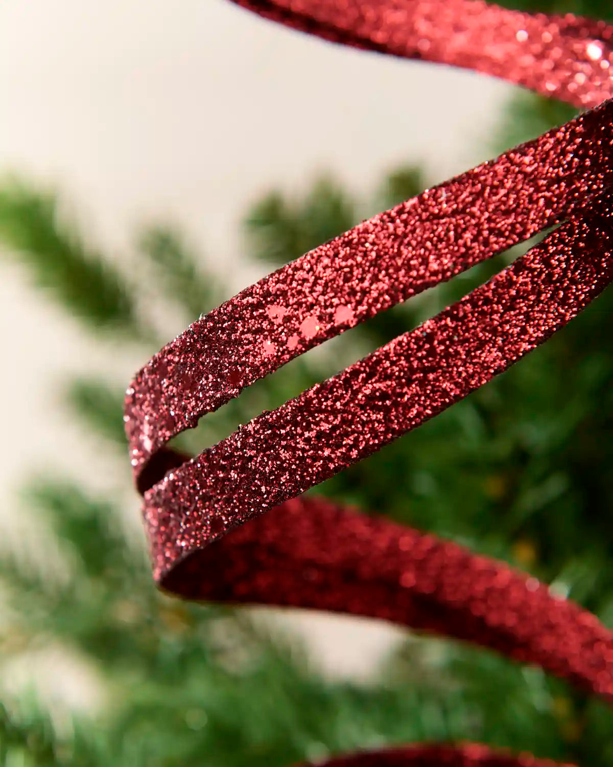 Close up burgundy Glitter Spiral Swirl Pick showing burgundy glitter details with green and cream blurred background