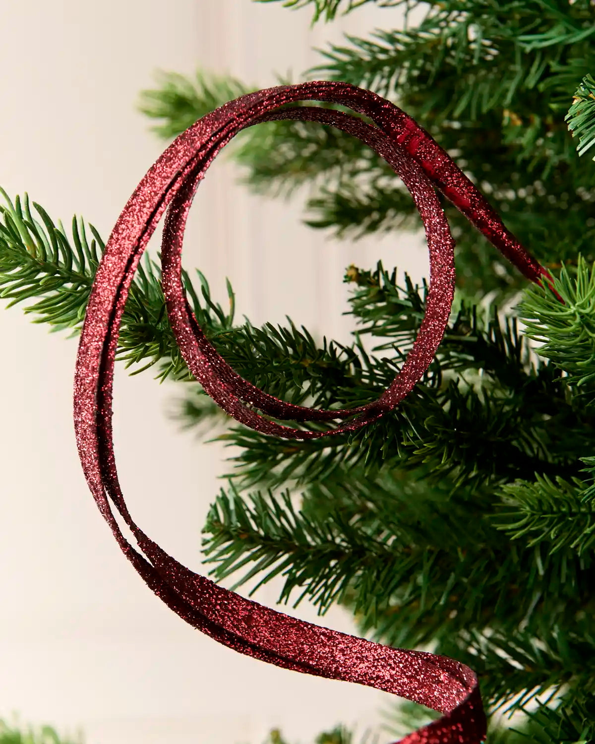 Close up burgundy Glitter Spiral Swirl Pick with green and cream blurred background
