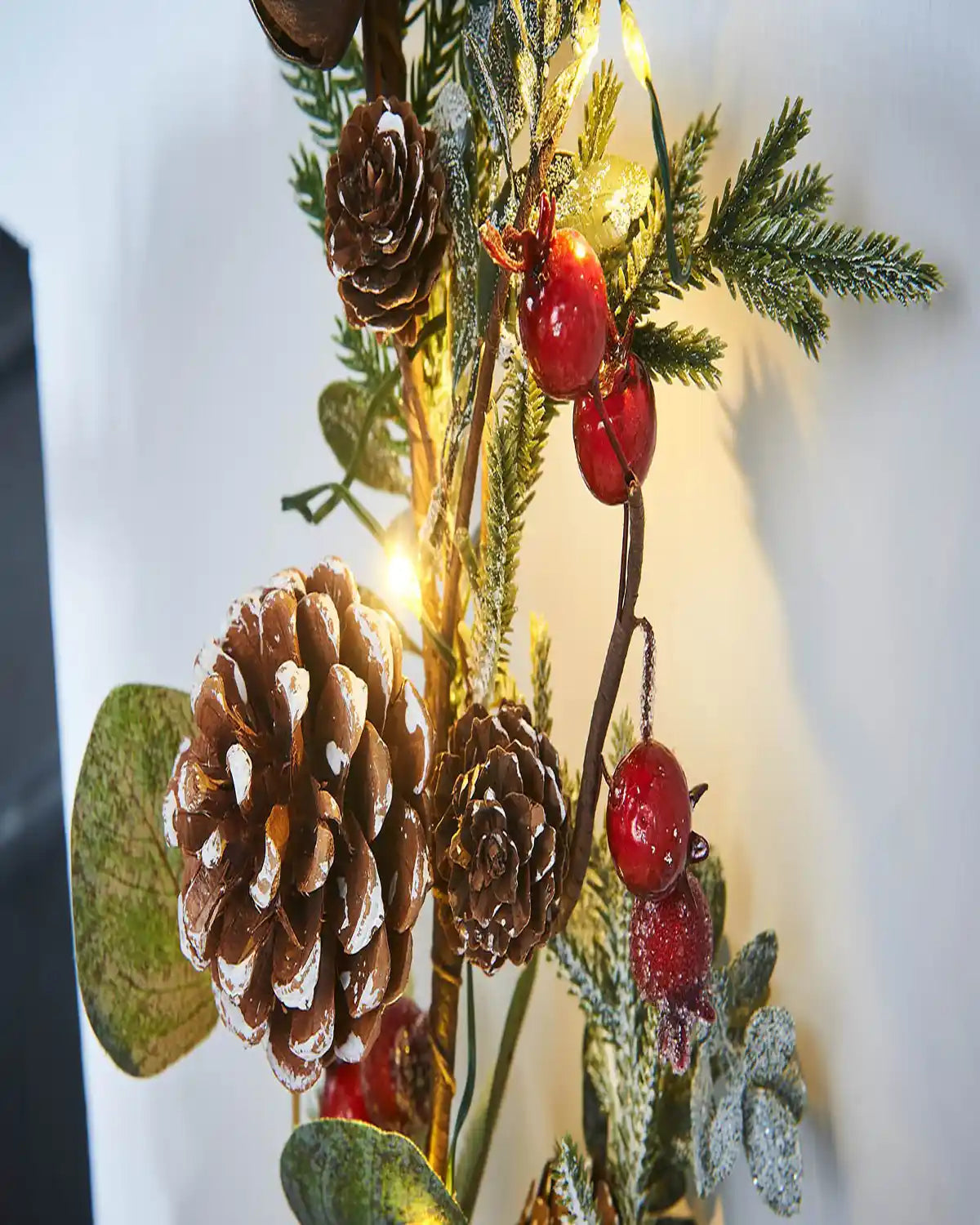 Close up decorative Christmas garland with Red berried, pinecones with lights