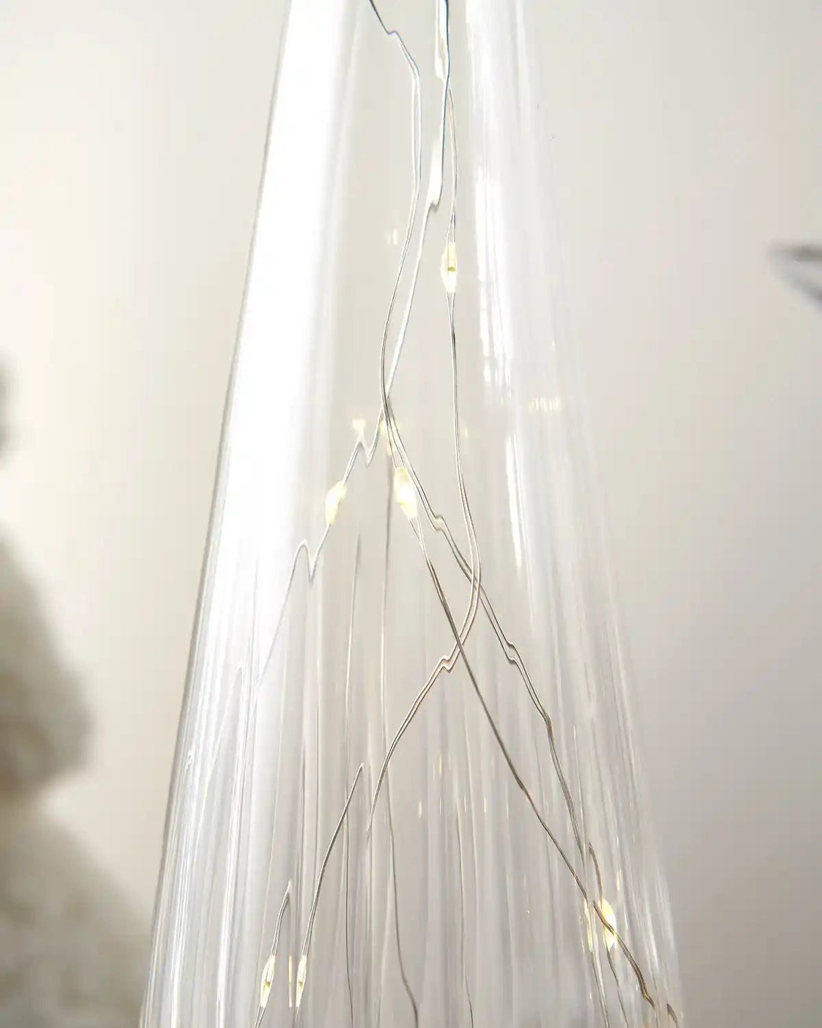 Close up glass Christmas tree ornament with Warm white lights against a white background
