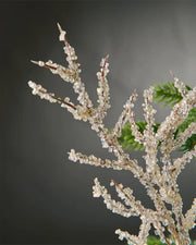 Close-up of gold beaded crystal spray attached to Christmas tree in front of grey background