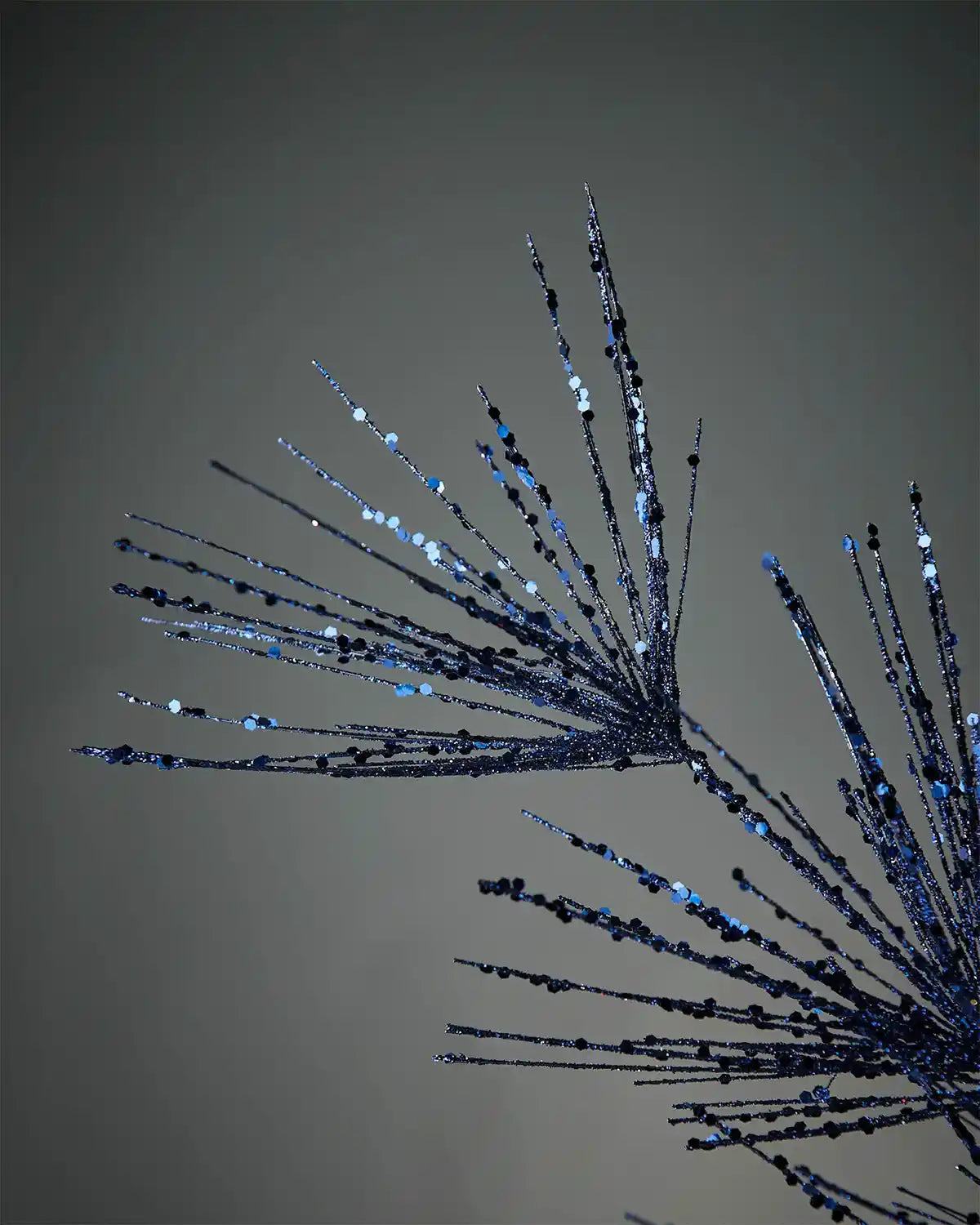 Close-up of navy blue glitter firework spray in front of grey background