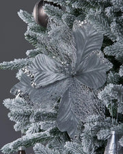 Close up of Decorative Poinsettia flower with silver lace-like petals on a white Christmas tree and silver baubles
