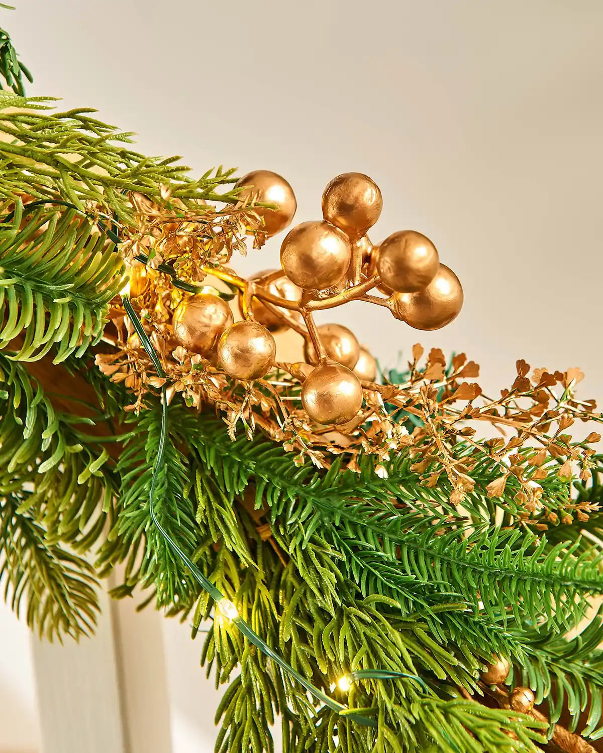 Close up of Gold berries and PVC and PE tips with warm white lights on a staircase banister