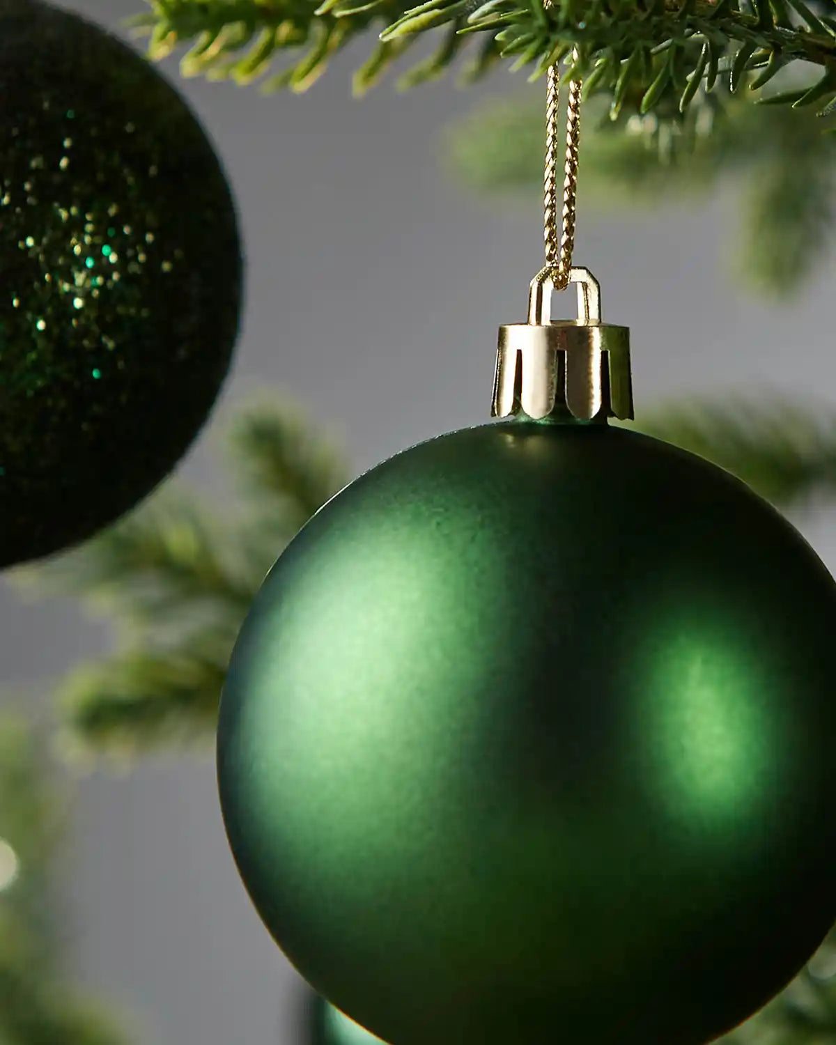Close up of Green Christmas baubles hanging on a tree branch with a blurred background
