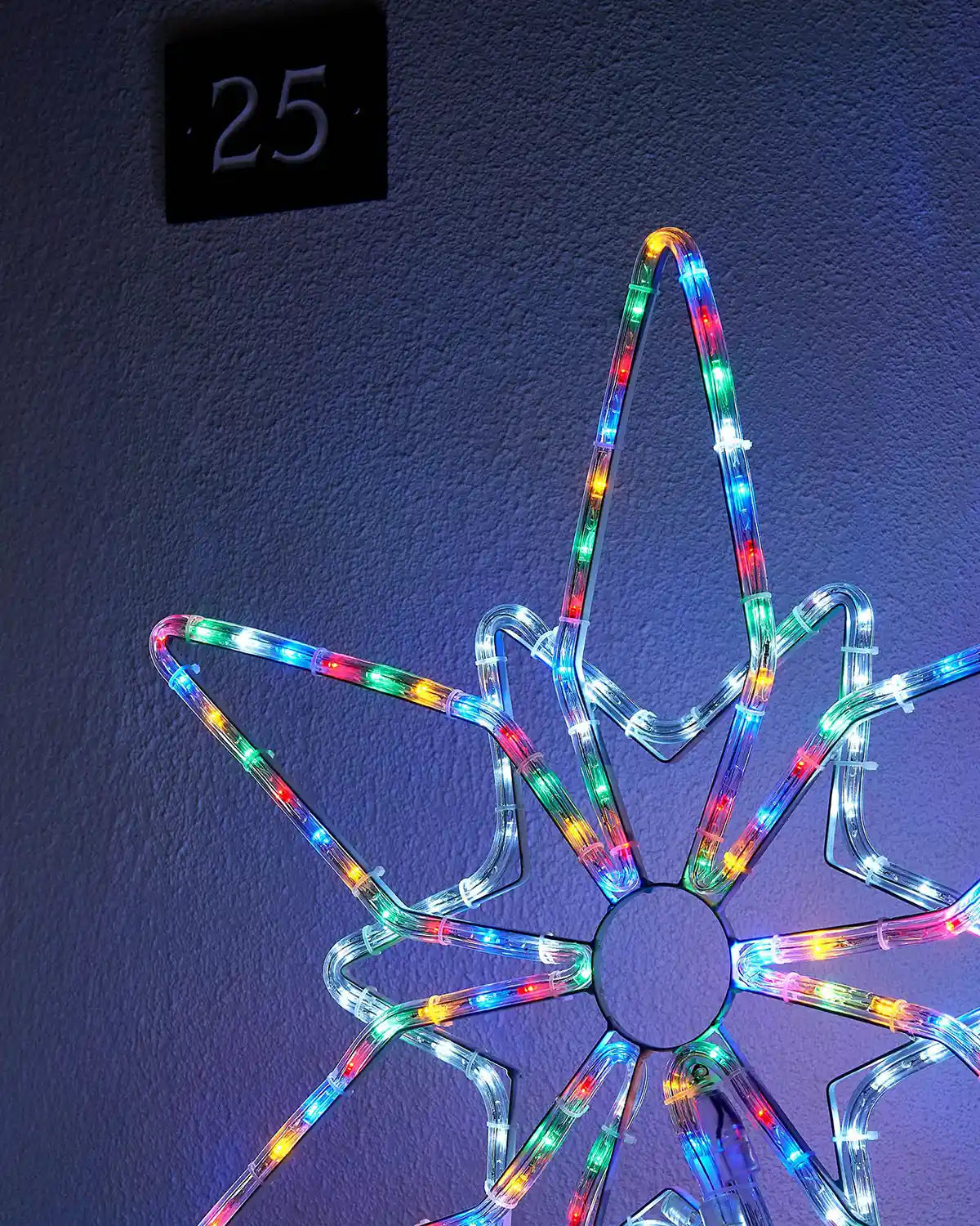 Close up of Multi colour LED Northern star on a blue garden wall