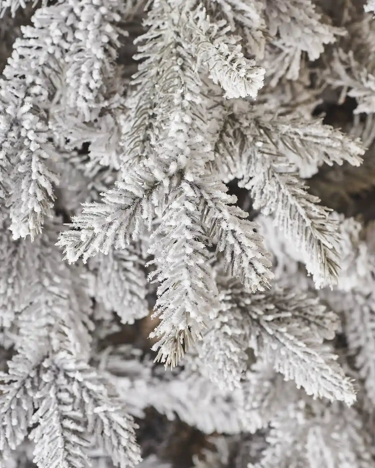 Close up of PVC and PE tips on a snow flocked Christmas tree.