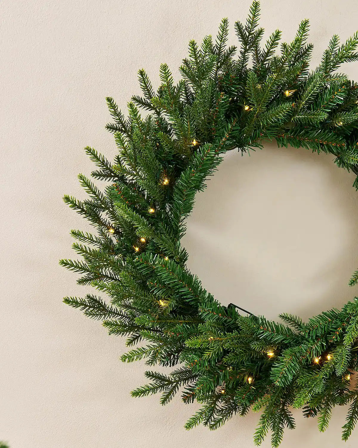 Close up of Pre-Lit Multi-Function Douglas Fir Wreath, 60 cm on a cream wall
