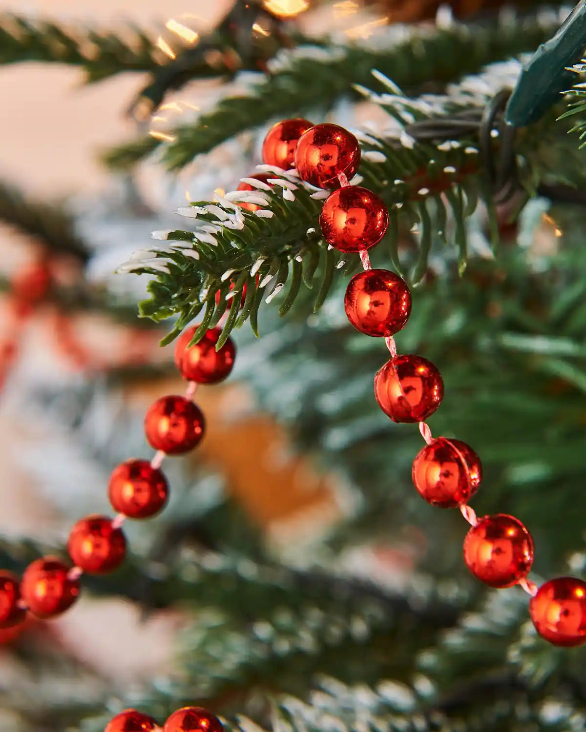Close up of Red bead garland on a Christmas tree with a blurred background
