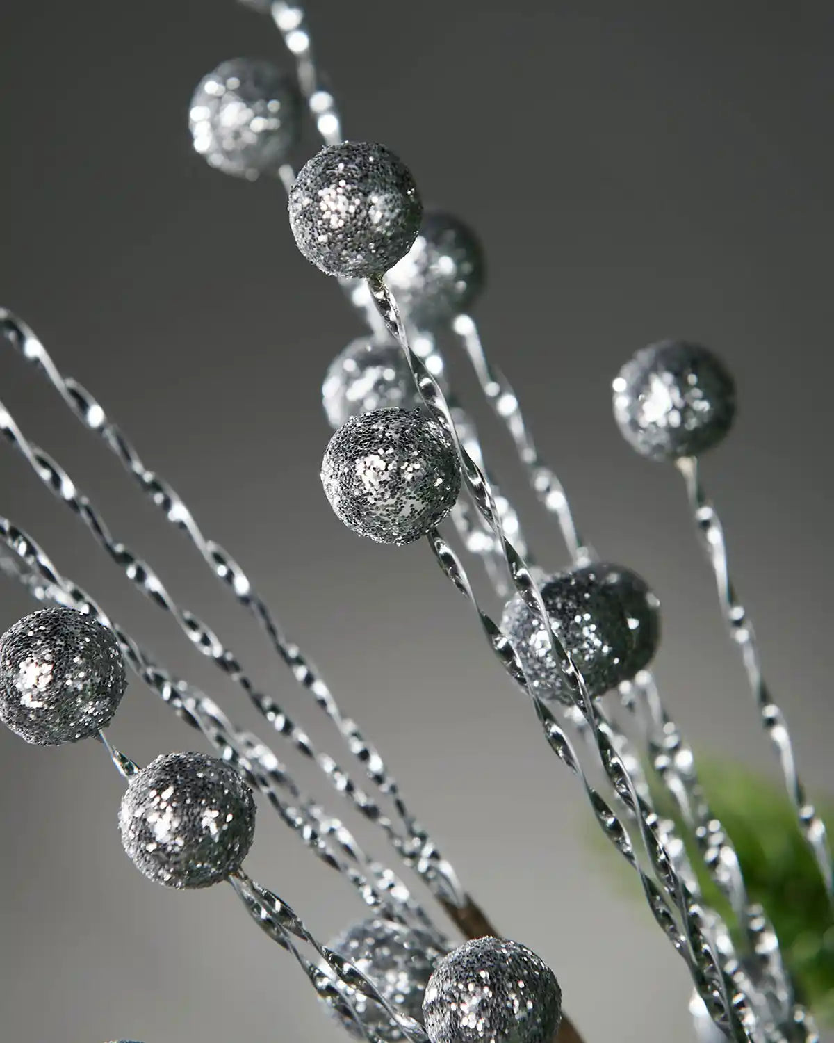 Close up of Silver decorative berries on branches against a grey blurred background