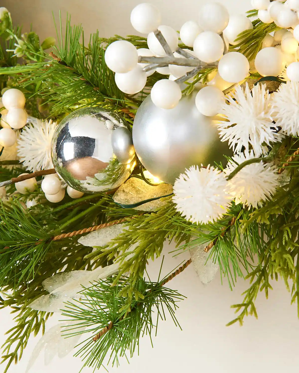 Close up of White berries, snowflakes and silver baubles on a Decorative Christmas wreath with greenery
