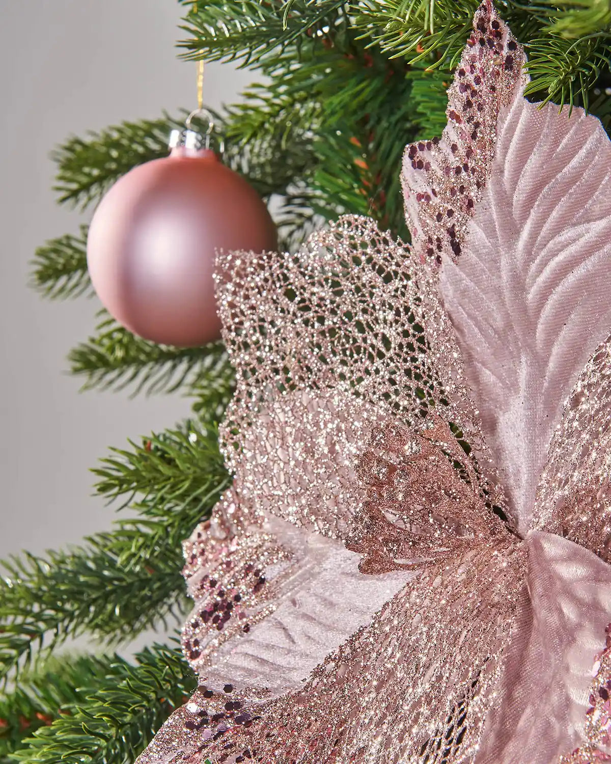 Close up of a Decorative pink glitter flower Poinsettia Green Christmas tree and pink bauble
