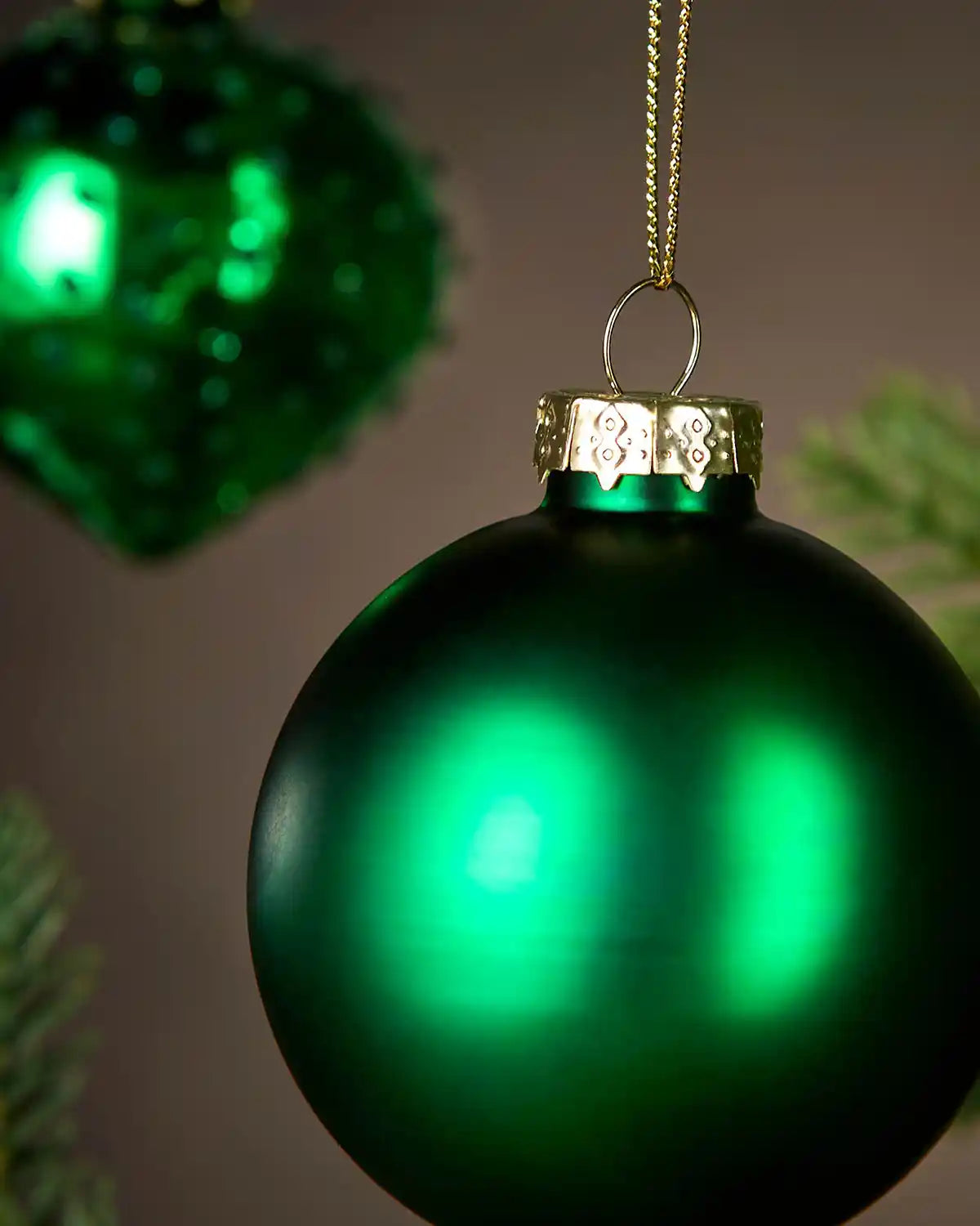 Close up of a Green Christmas bauble with gold cap on a blurred background