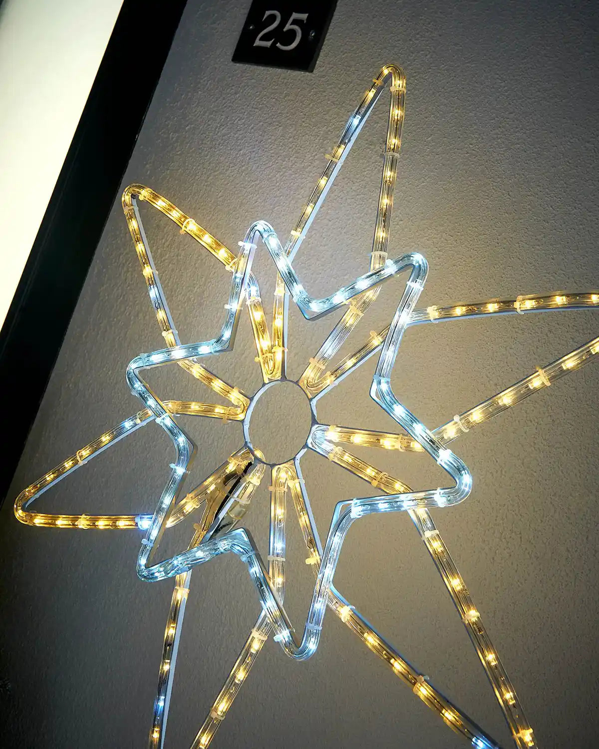 Close up of a Warm white and ice white LED Northern star on light coloured garden wall