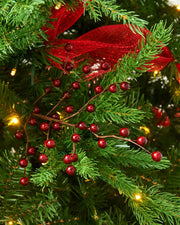 Close up of a decorative Christmas red berry spray  and ribbons on a green Christmas tree branch