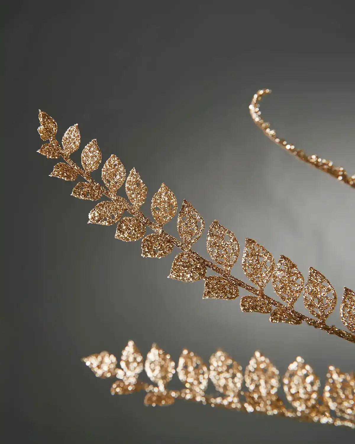 Close up of a decorative glitter gold leaf branch on a Christmas tree against a dark background