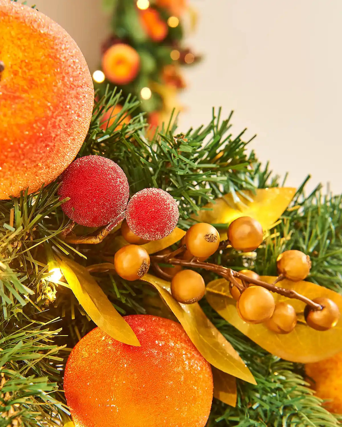 Close up of artificial frosted oranges and peaches on a staircase banister against a Cream background