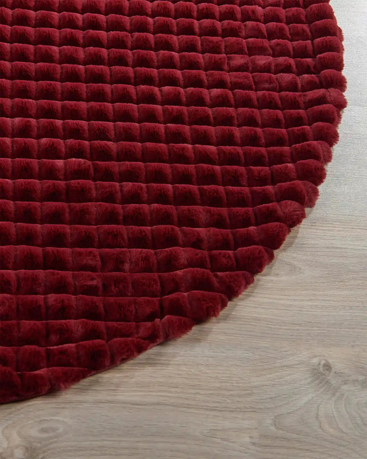 Close-up of burgundy diamond faux fur tree skirt on light wooden flooring showing the soft texture of skirt