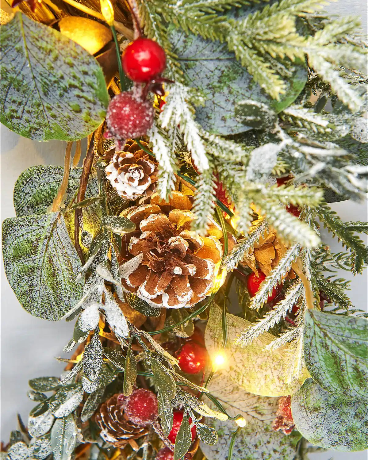 Close up of decorative Christmas wreath with pine cones, berries, and lights