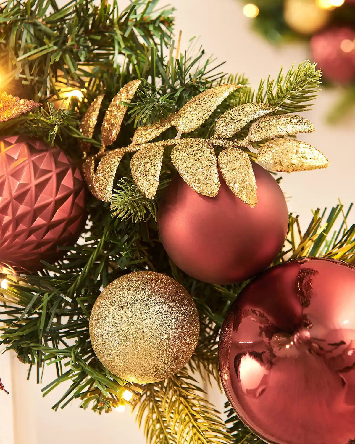 Close up of decorative Christmas wreath with red and gold ornaments and greenery.