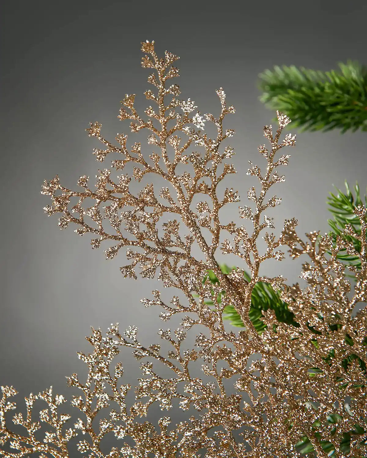 Close up of decorative gold glitter artificial plant stem with small branches on a Christmas tree 