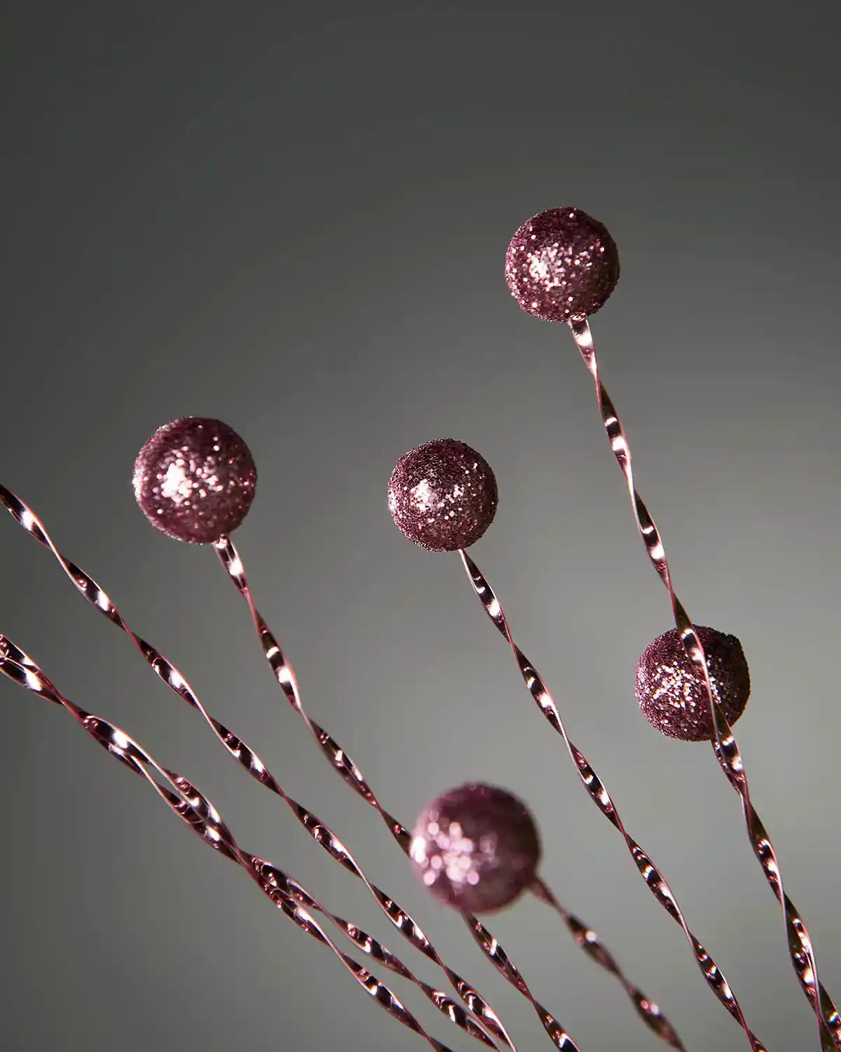 Close up of decorative vine with glittery berries on a grey background