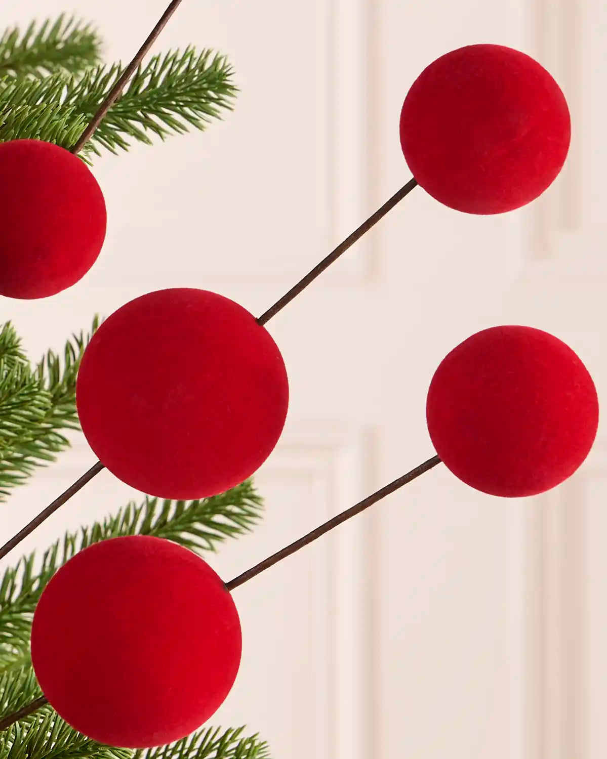 Close up of five Red velvet bauble pick on a Christmas tree against a light background