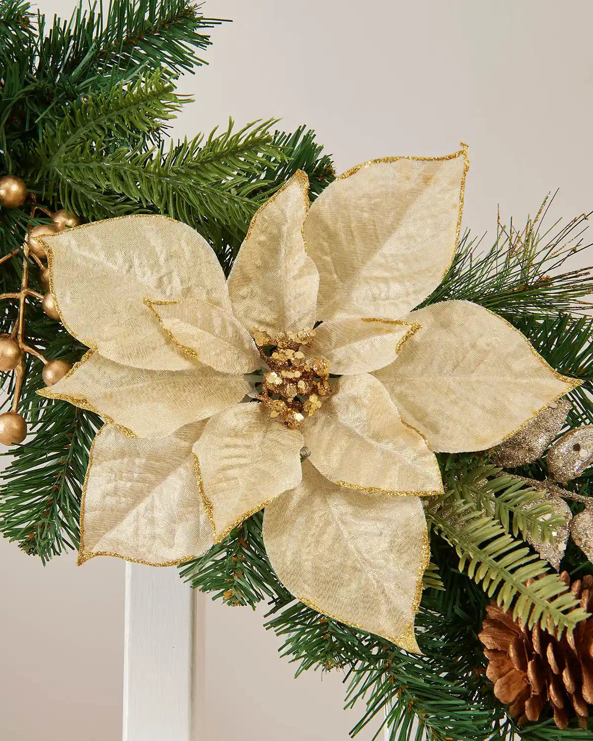 Close-up image of the green staircase garland, highlighting the gold fabric foliage and pinecone decoration