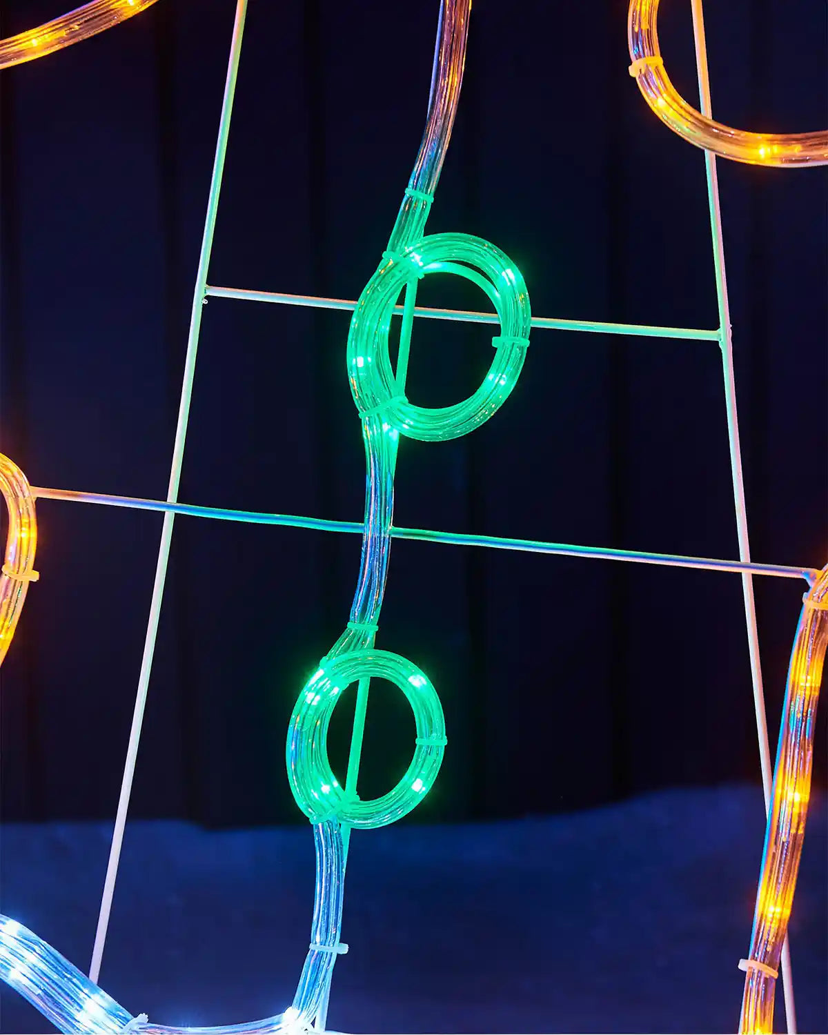 Close up of green buttons on LED gingerbread man against a dark fence