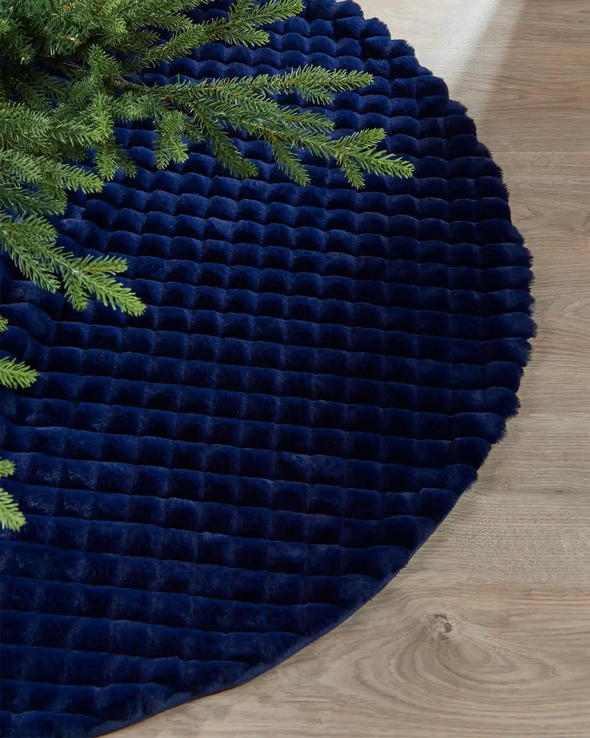 Close-up of navy faux fur diamond tree skirt on light wooden floor, highlighting the soft texture of the skirt