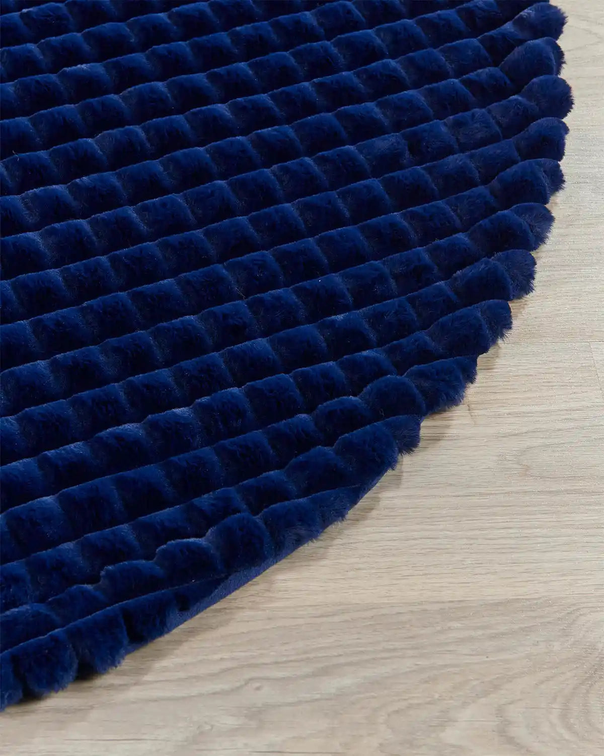 Close-up of navy faux fur diamond tree skirt edge. highlighting the soft texture on light wooden flooring