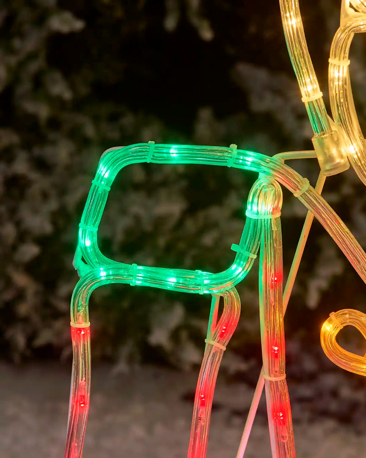Close up of nutcrackers green shoulder pad against a snowy garden bush