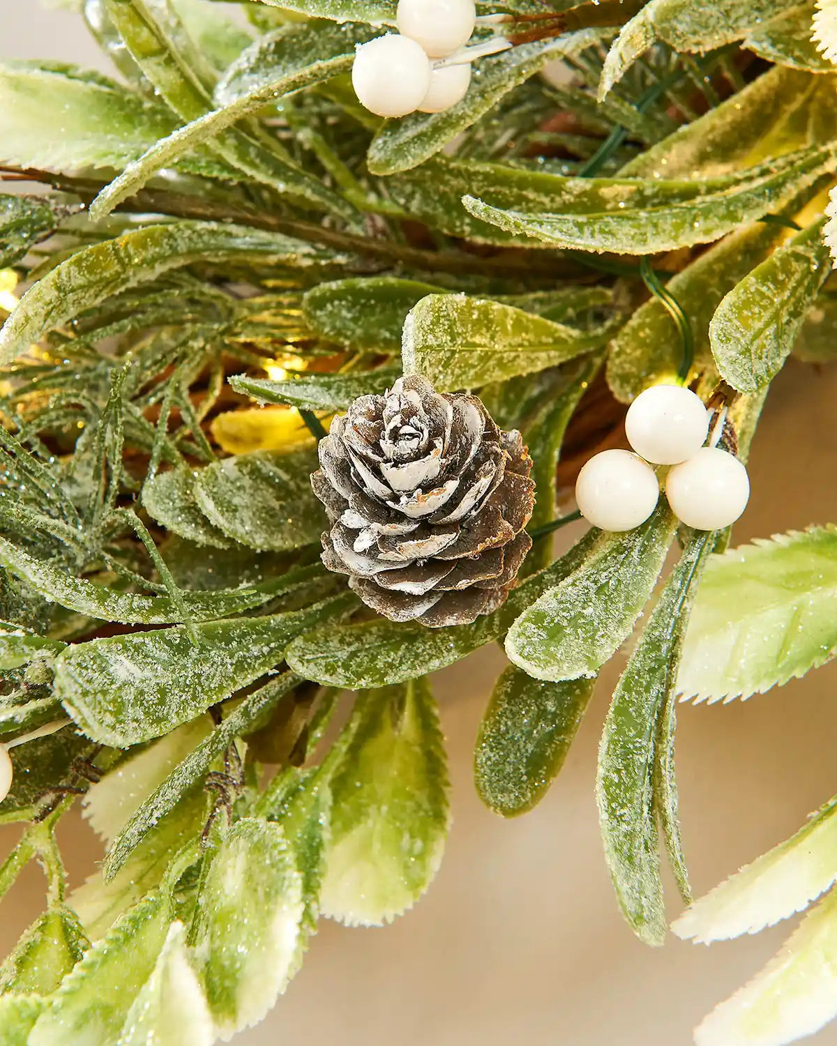Close up of  pinecones, white berries and small lights on a beige background