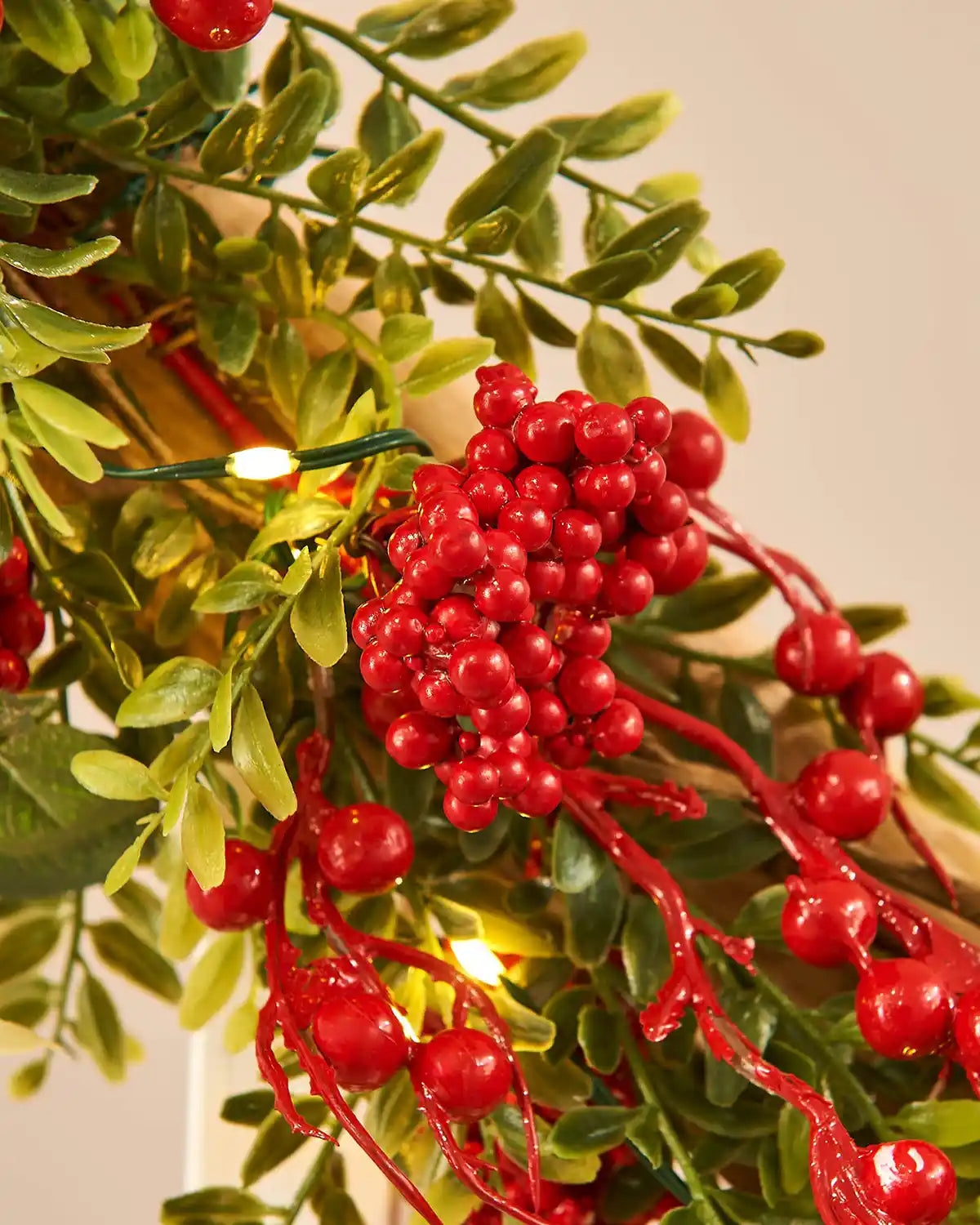 Close up of red berries and green leaves on a neutral background