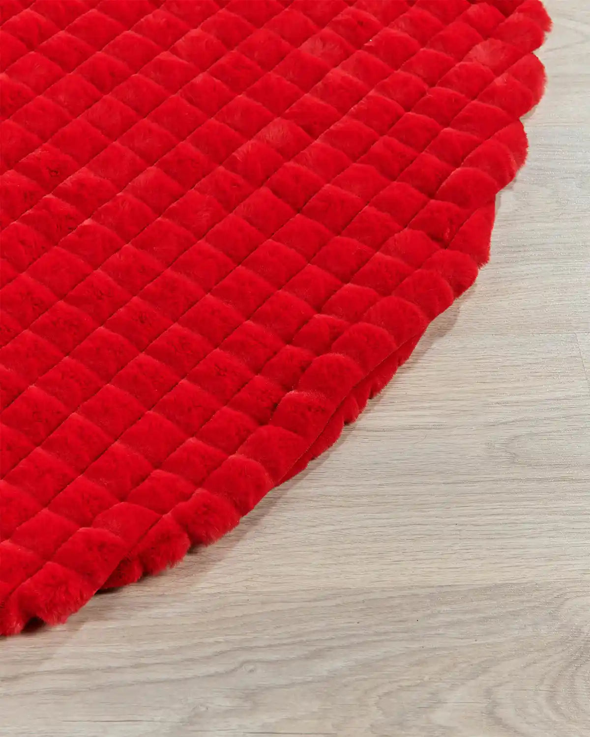 Close-up of red faux fur diamond tree skirt edge highlighting the soft texture on light wooden flooring