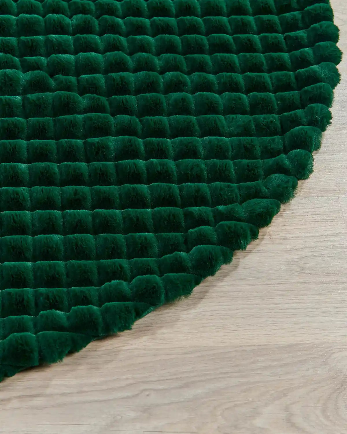 Close-up of sage green faux fur diamond tree skirt on wooden flooring, highlighting the soft quality of the tree skirt