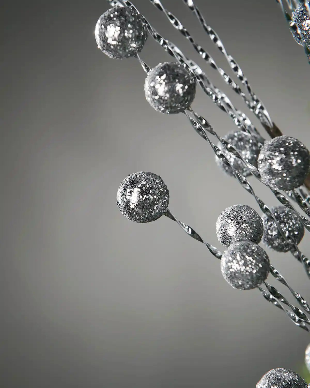 Close up of silver glitter berries tree spray on a grey background