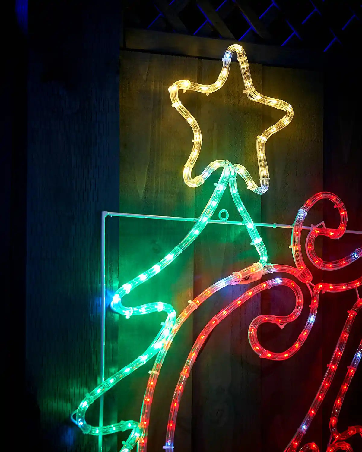 Close up of the Green Christmas tree and Yellow Star on a Merry Christmas Silhouette sign on a garden fence
