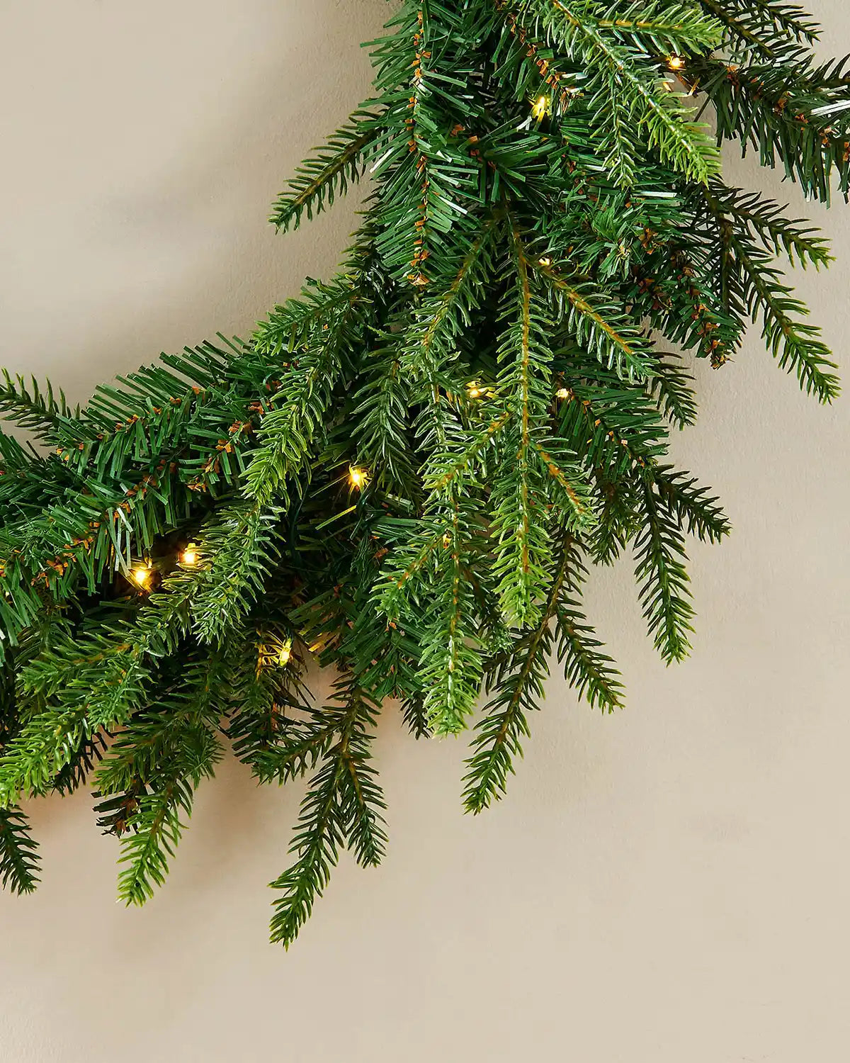 Close up of the bottom of Pre-Lit Multi-Function Douglas Fir Wreath, 60 cm on a cream wall
